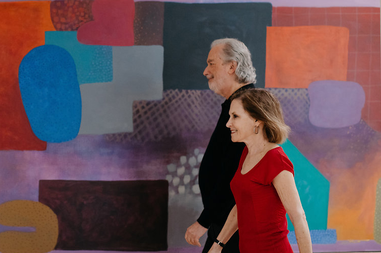A photo of a couple walking past a large painting