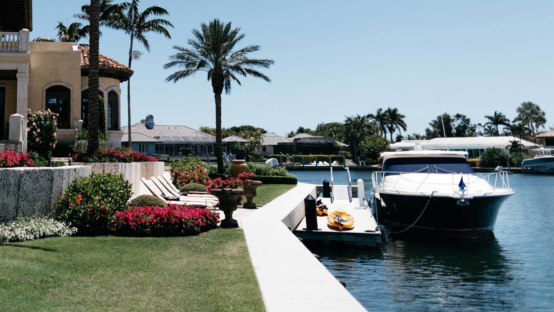 A photo of a small boat docked in the backyard of a luxurious Florida home.