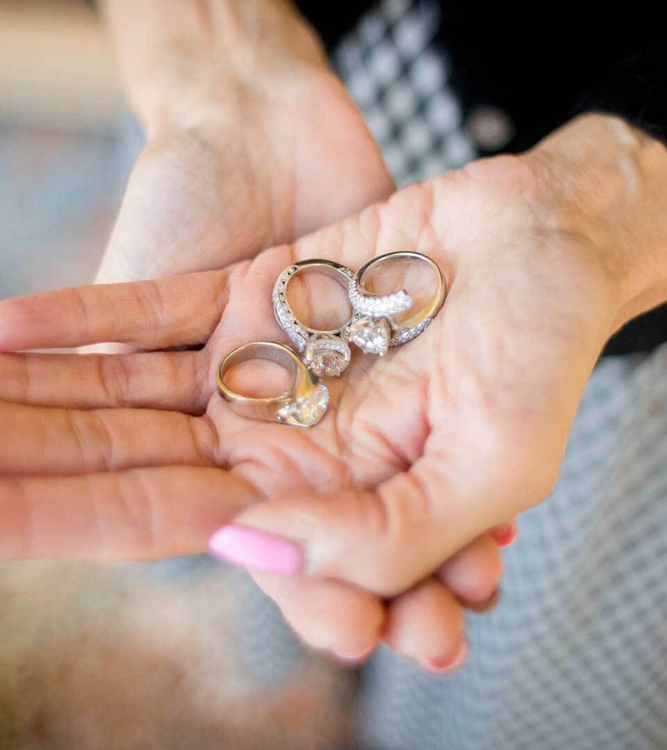 A photo of a woman's hands holding three diamond rings.