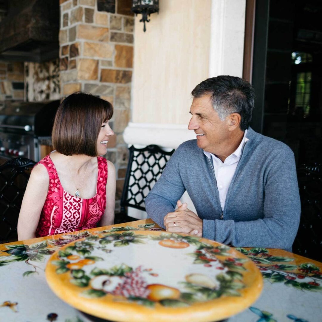 A couple sitting outside at a decorated table smiling and having a conversation.