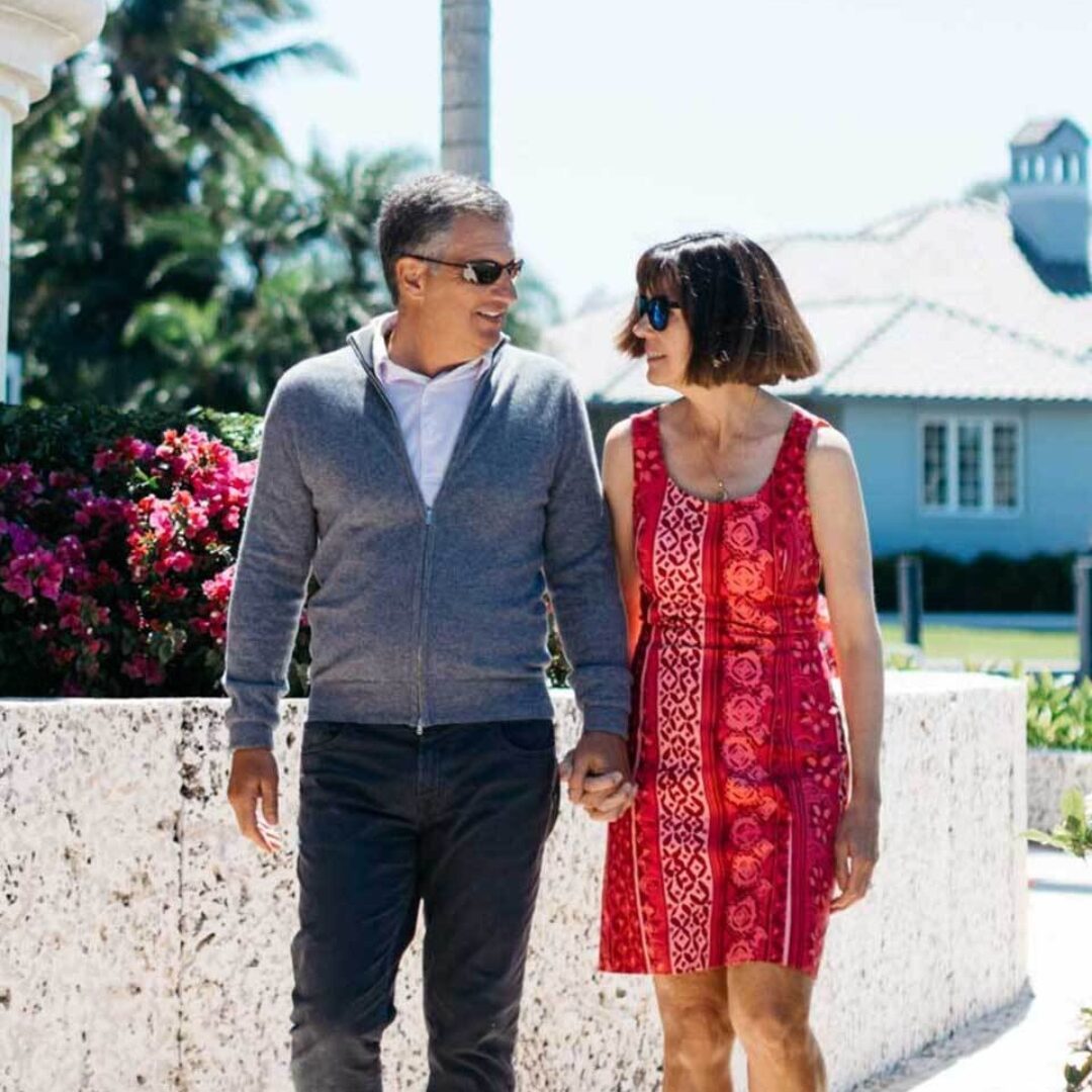 A stylish couple walking together outside in a tropical location.
