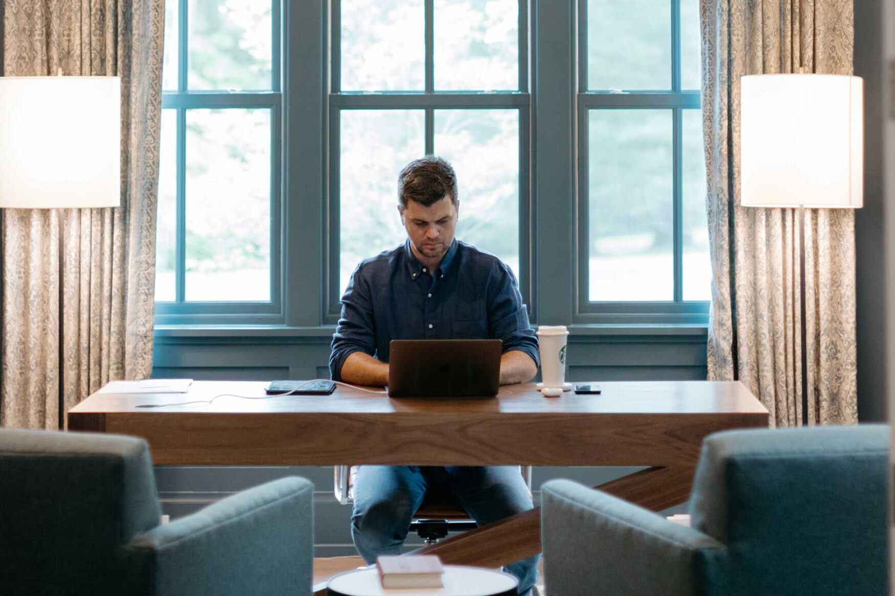 A photo of a man on his laptop in a large, well decorated home office.