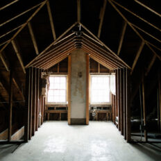 A photo of a large interior room of a home stripped down to the studs.