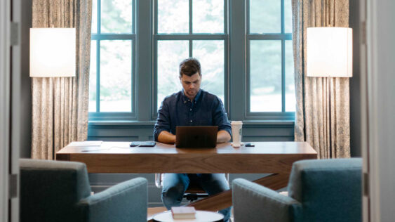 A photo of a man on his laptop in a large, well decorated home office.