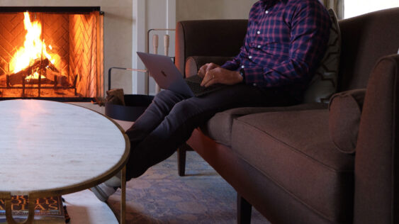 A close-up photo of a man on a laptop in his living room.