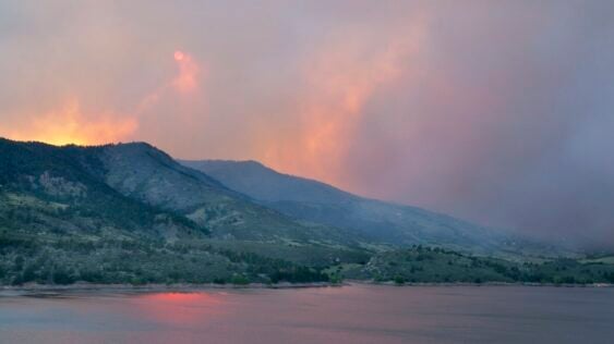 A landscape photo of distant hills with smoke coming off of them