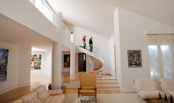 An image of a couple walking down a spiral staircase in a modern, open home.