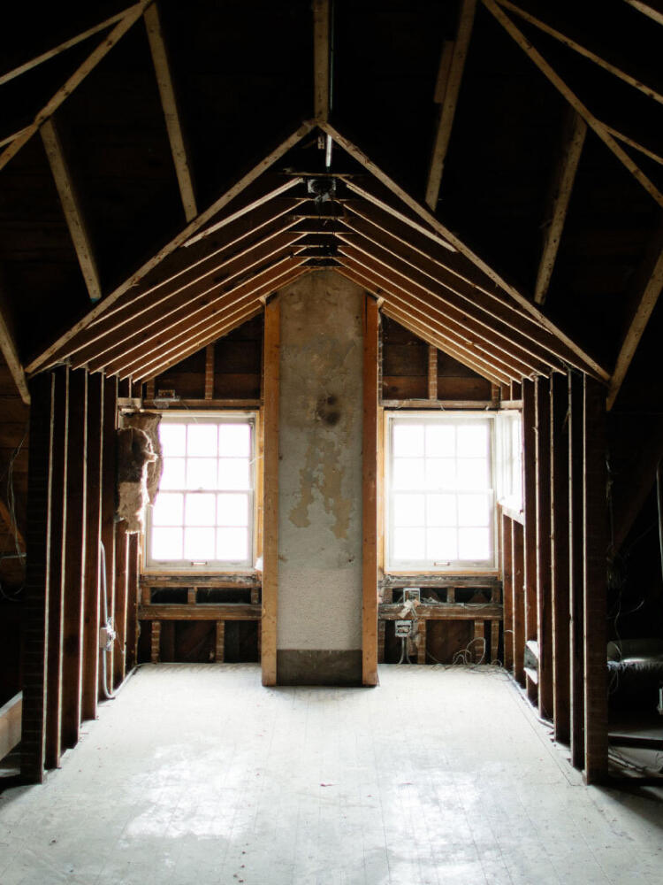A photo of a large interior room of a home stripped down to the studs.