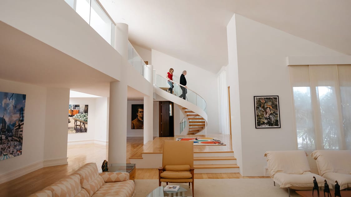 An image of a couple walking down a spiral staircase in a modern, open home.