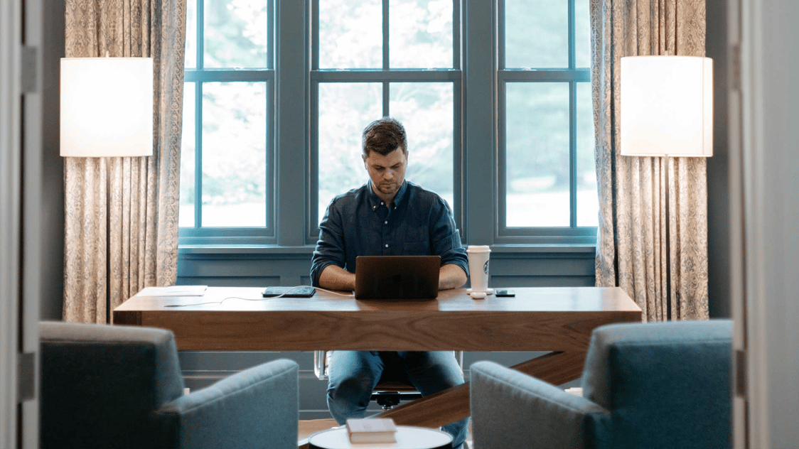 A photo of a man on his laptop in a large, well decorated home office.