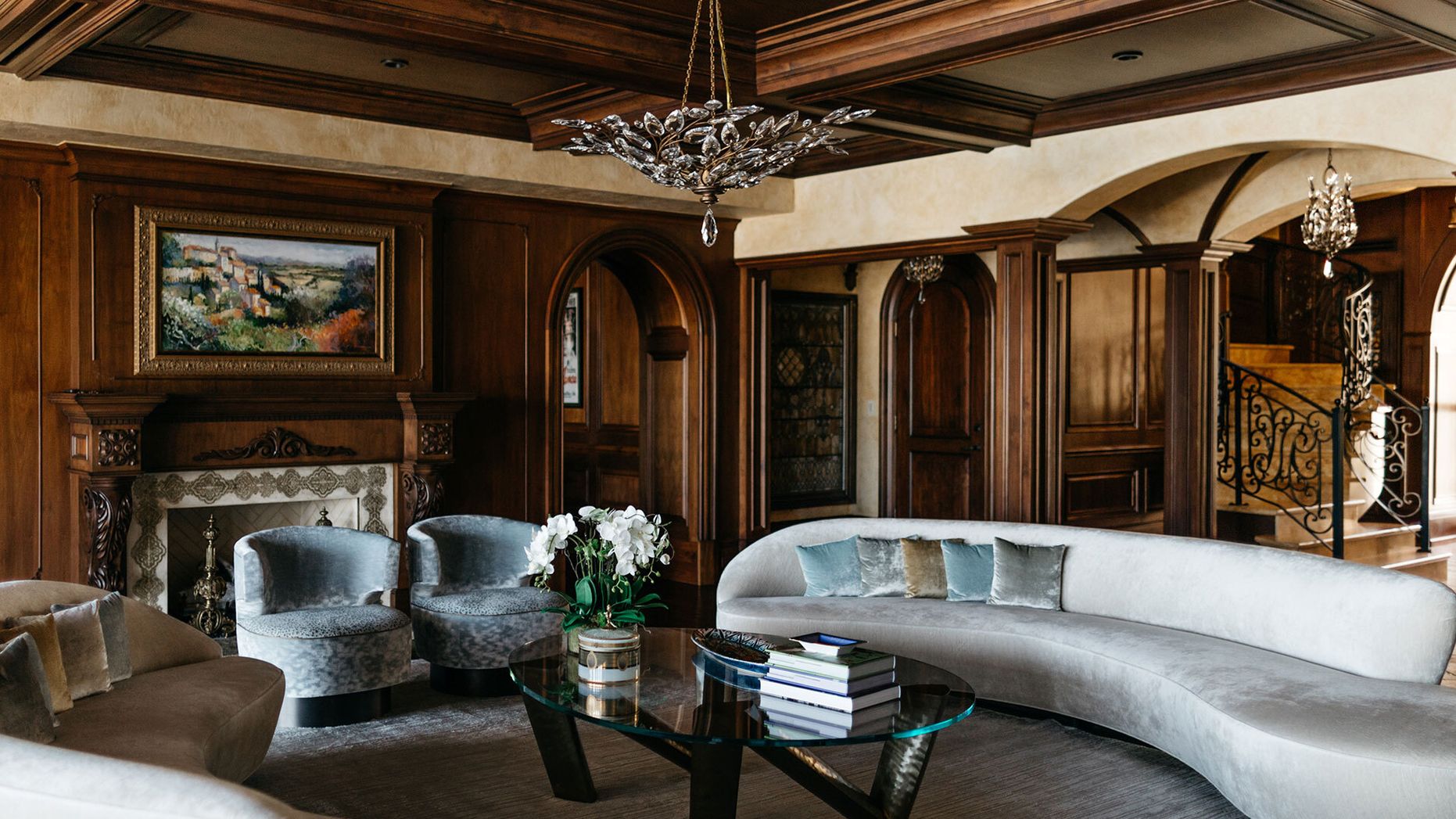 A photo of a luxurious living room with wooden millwork walls and a long, velvet sofa.