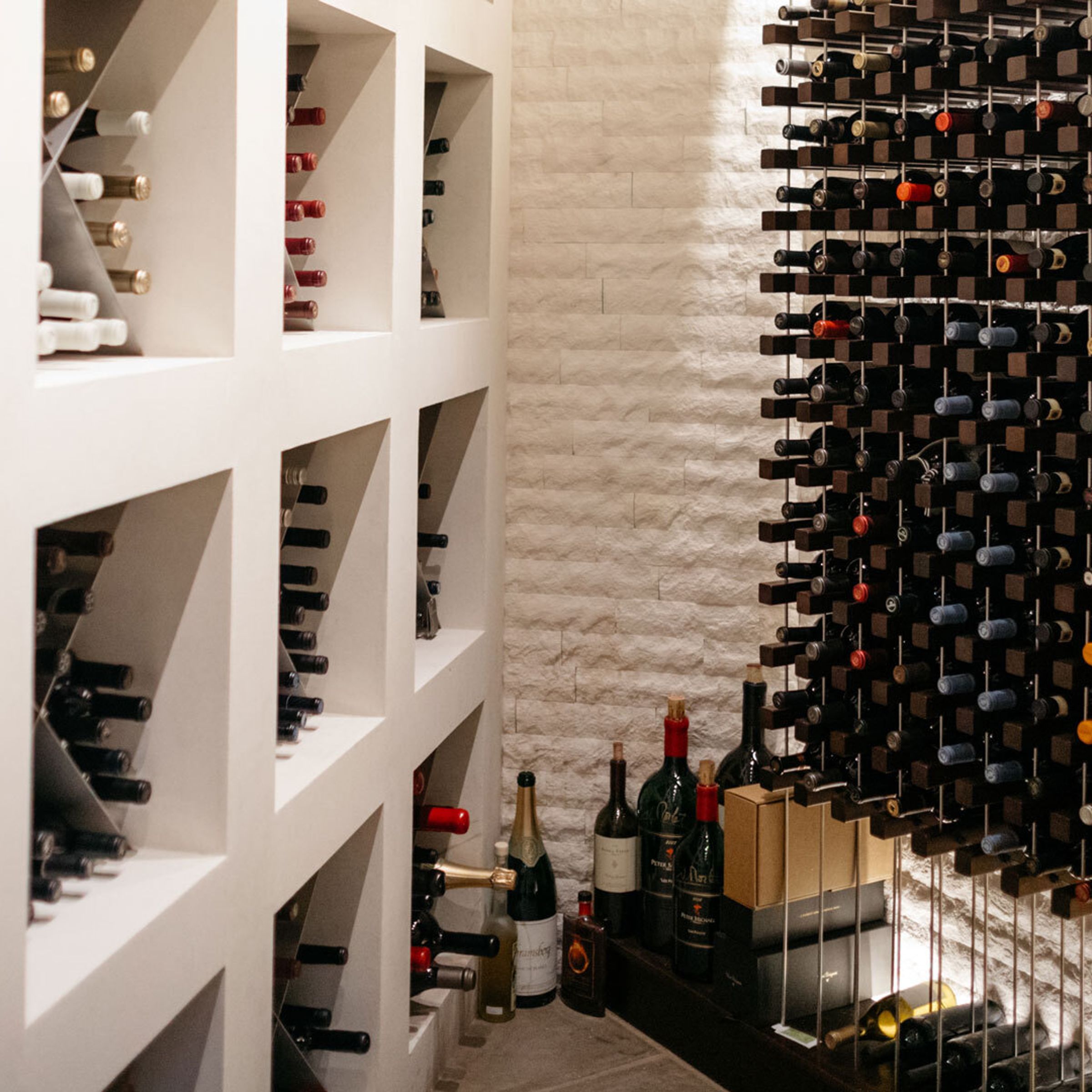 A photograph of a large wine collection inside a clean, white wine cellar.