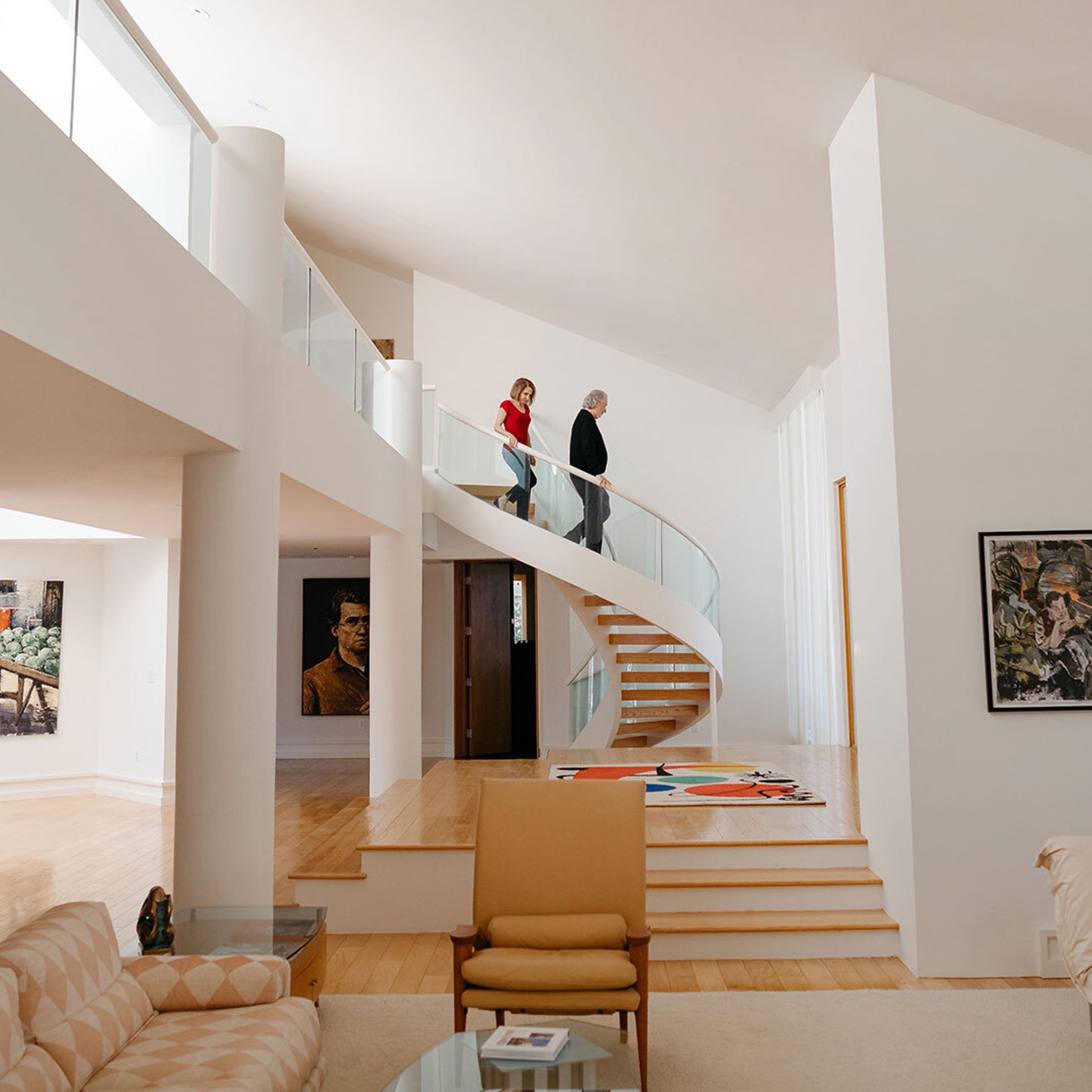 An image of a couple walking down a spiral staircase in a modern, open home.