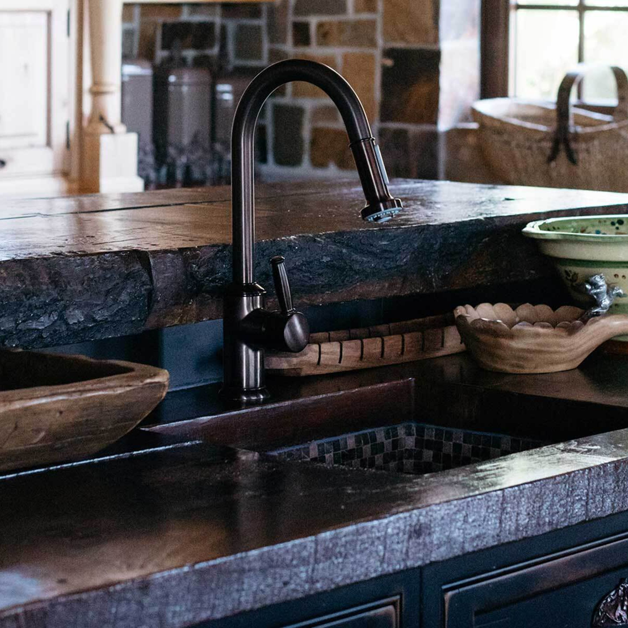 A photo of a beautifully decorated kitchen with a focus on a bronze sink fixture.