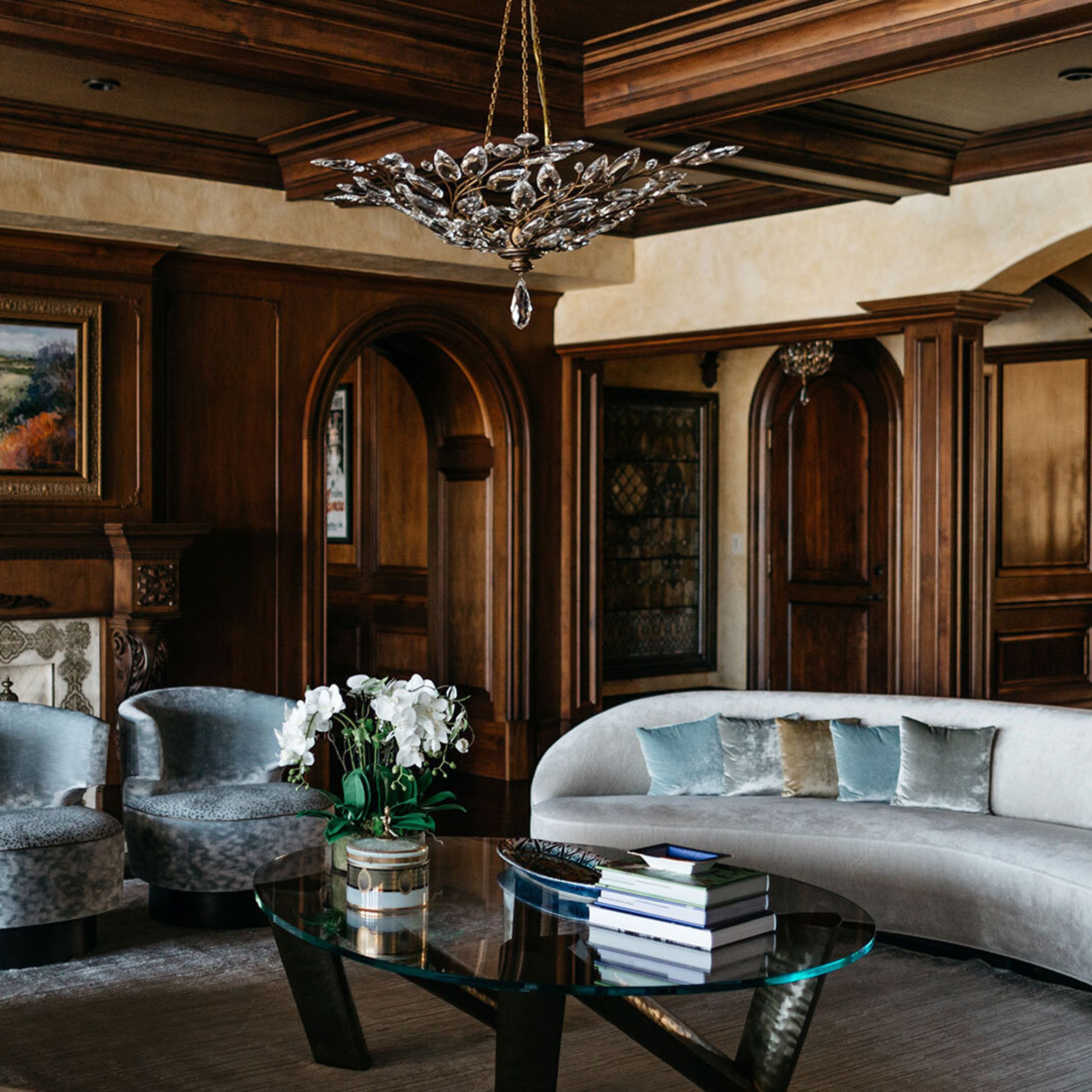 A photo of a luxurious living room with wooden millwork walls and a long, velvet sofa.