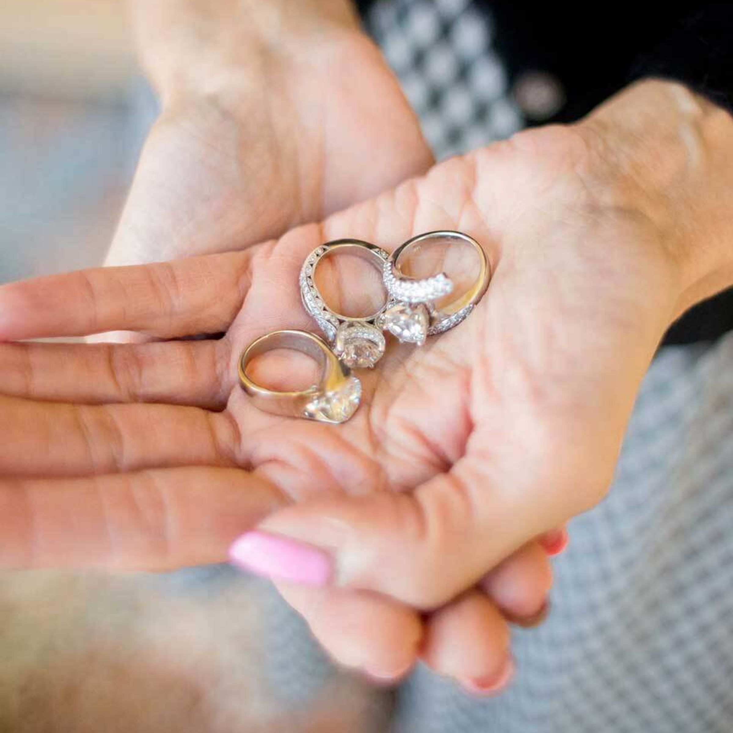 A photo of a woman's hands holding three diamond rings.