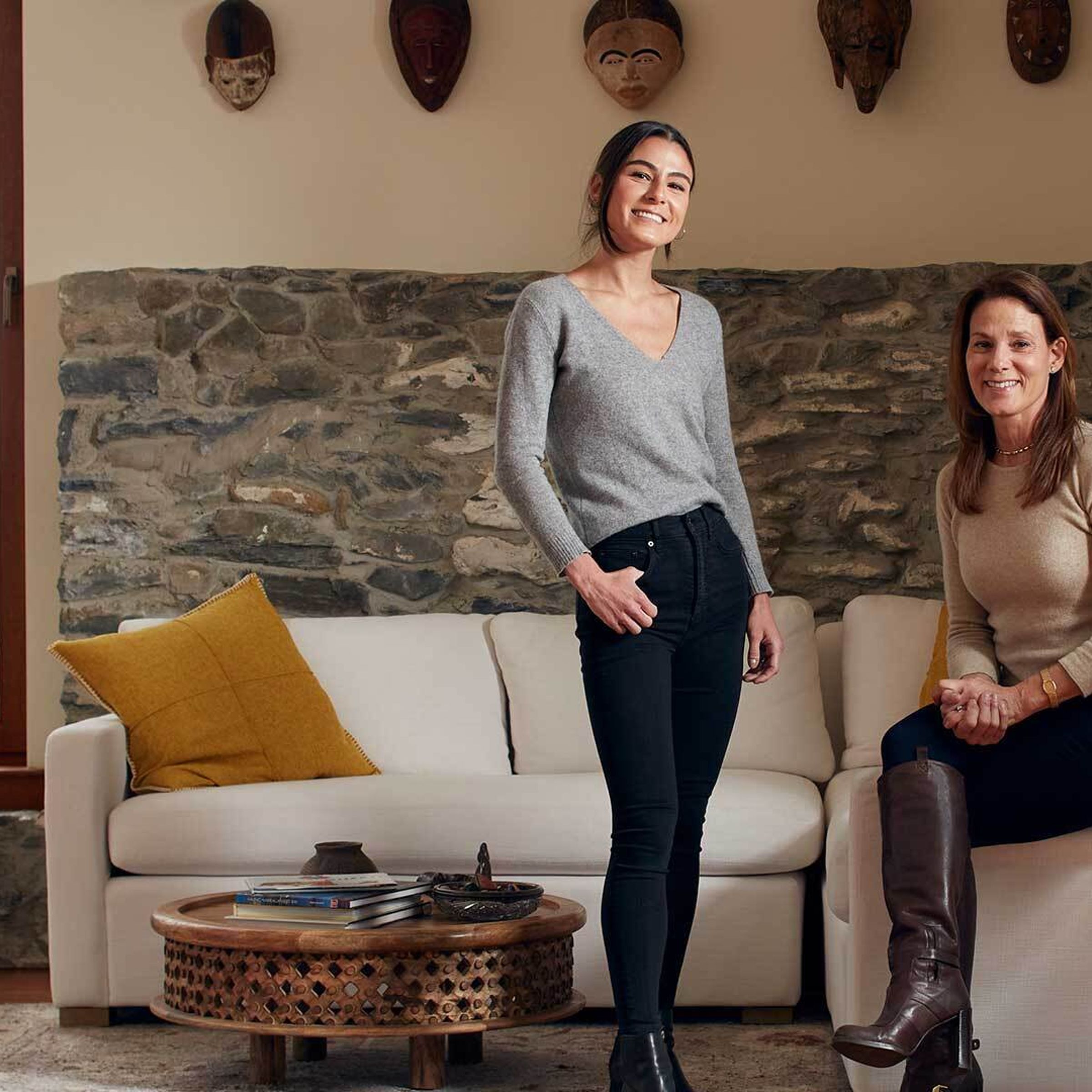 A stylish woman and her daughter pose facing the camera in their living room.
