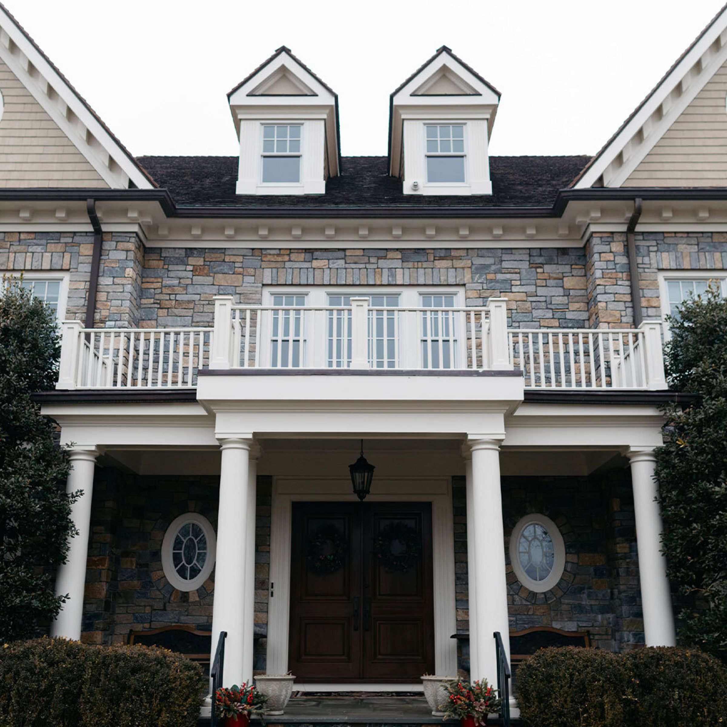 A photo looking up at the exterior of a large stone house during winter.