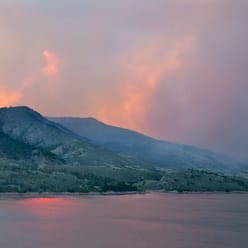 A landscape photo of distant hills with smoke coming off of them