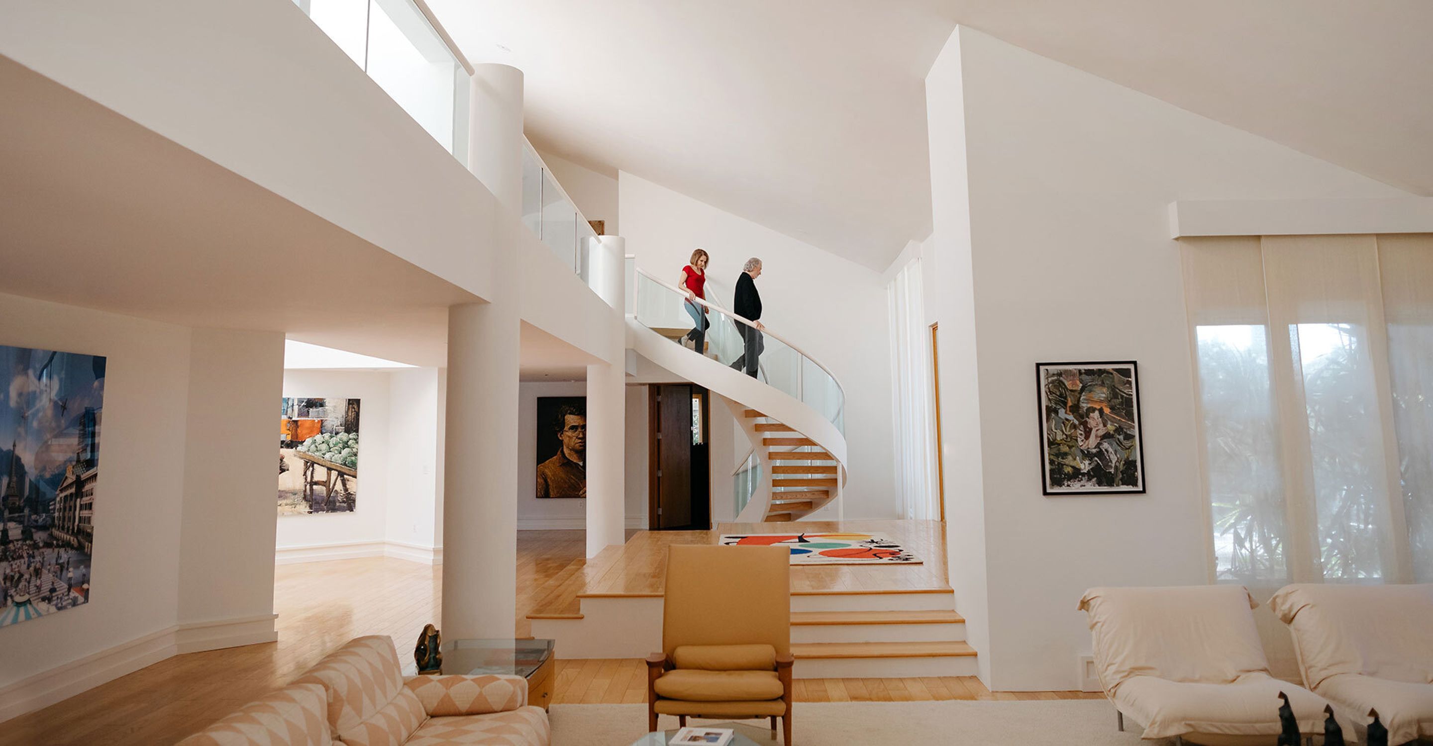 An image of a couple walking down a spiral staircase in a modern, open home.