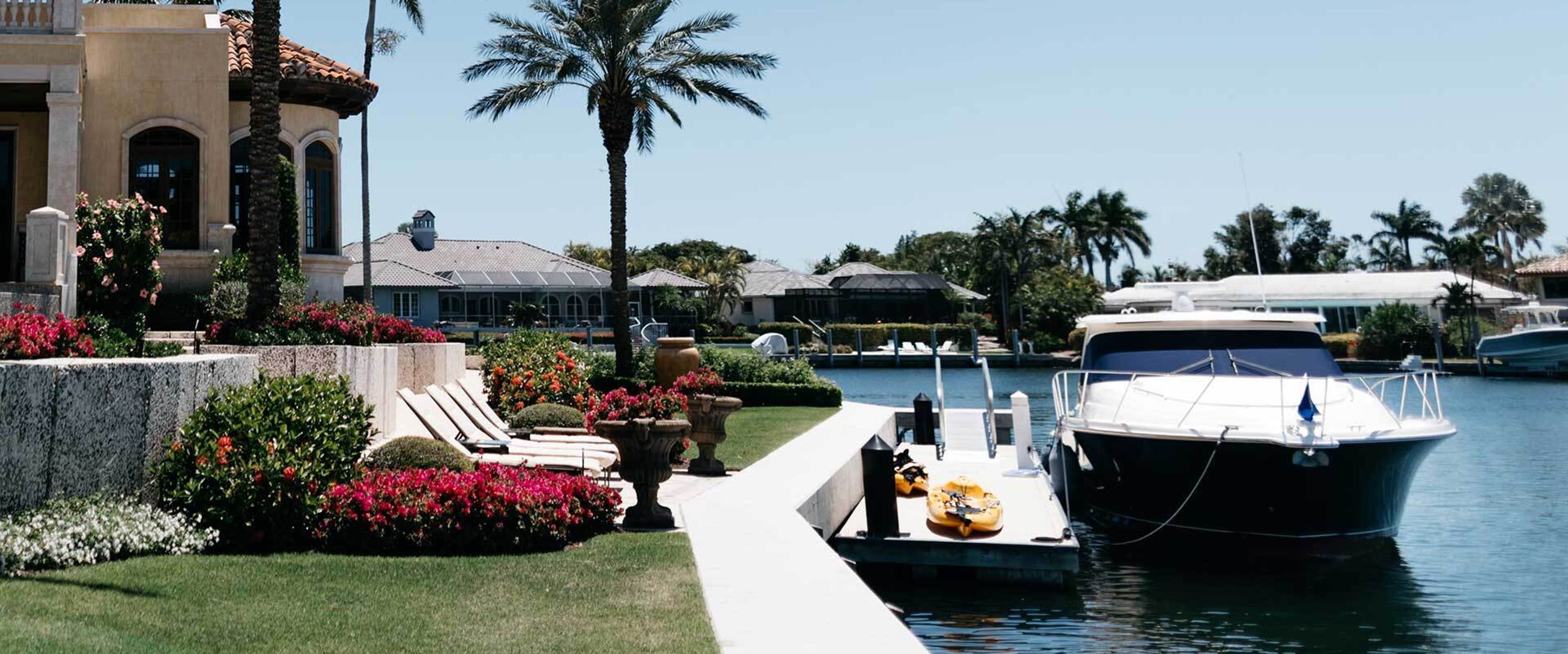 A photo of a small boat docked in the backyard of a luxurious Florida home.
