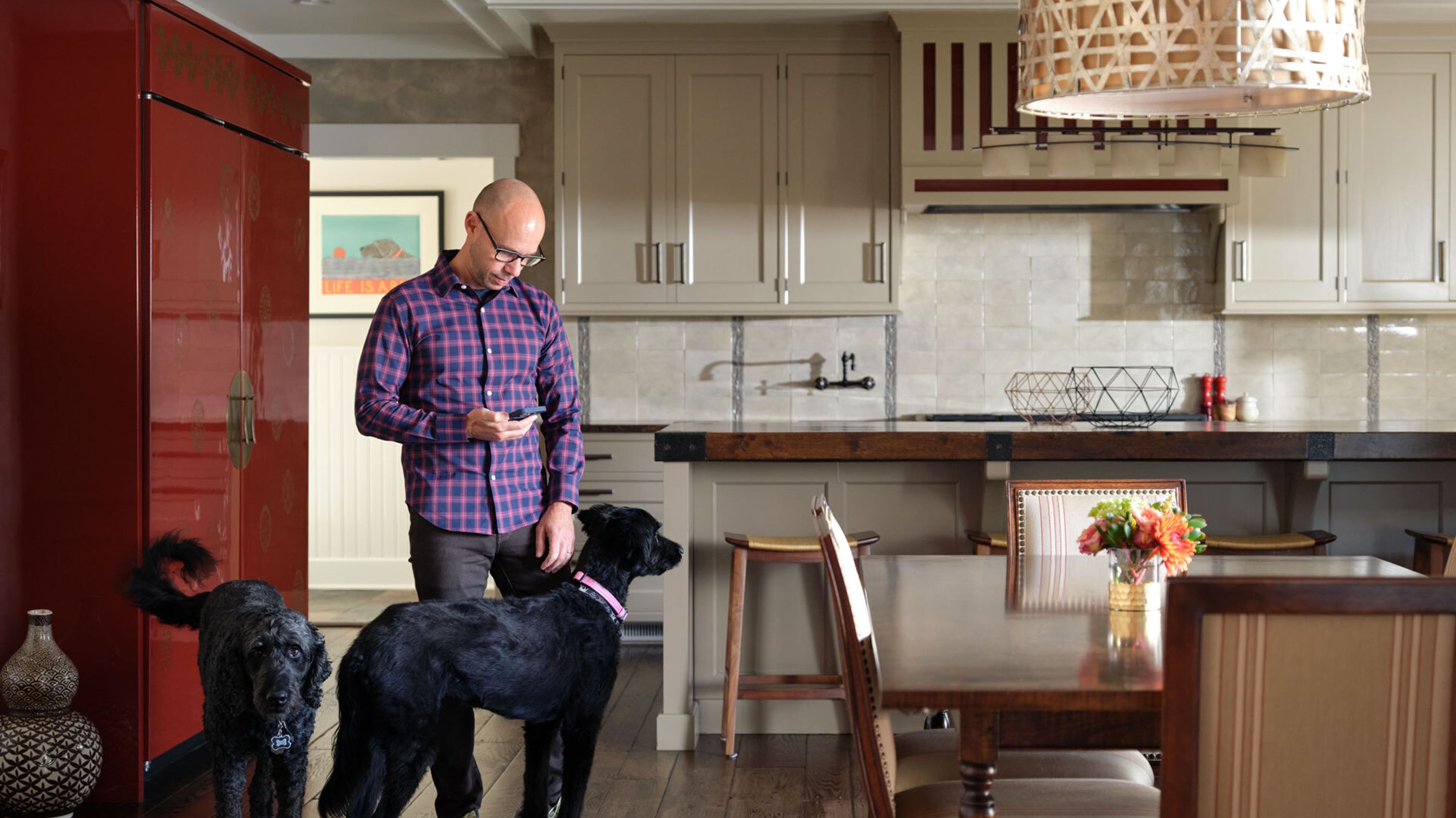 A photo of a man using his cellphone in a large luxurious kitchen.