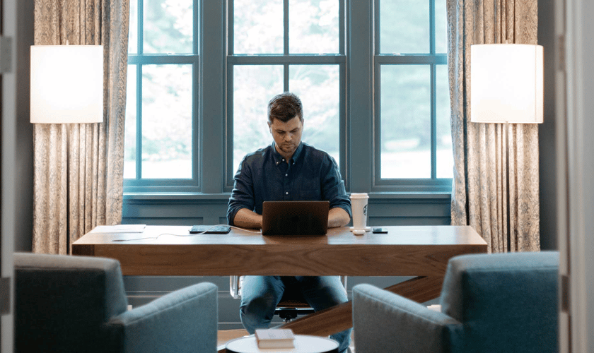 A photo of a man on his laptop in a large, well decorated home office.
