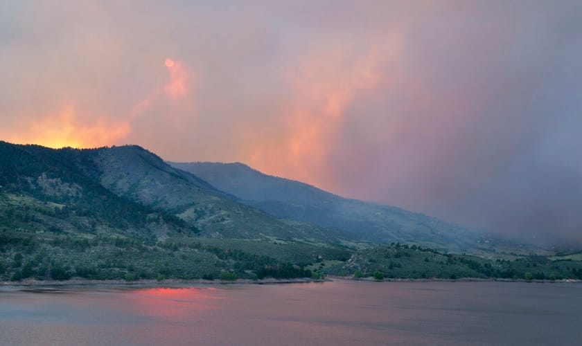A landscape photo of distant hills with smoke coming off of them